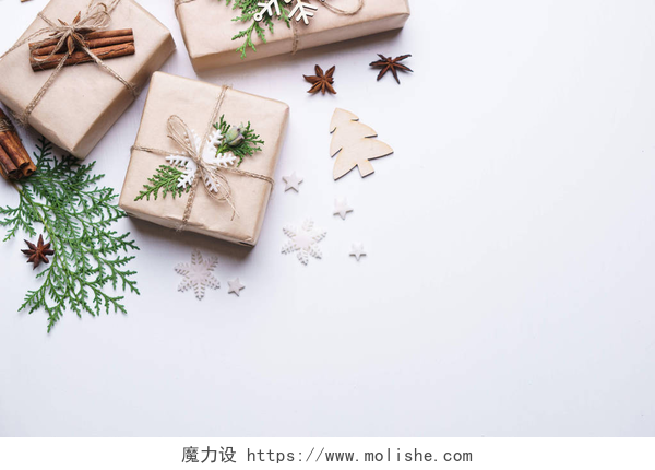 白色桌子上的礼品盒和绿色的树叶圣诞礼物在白色背景下的构图
